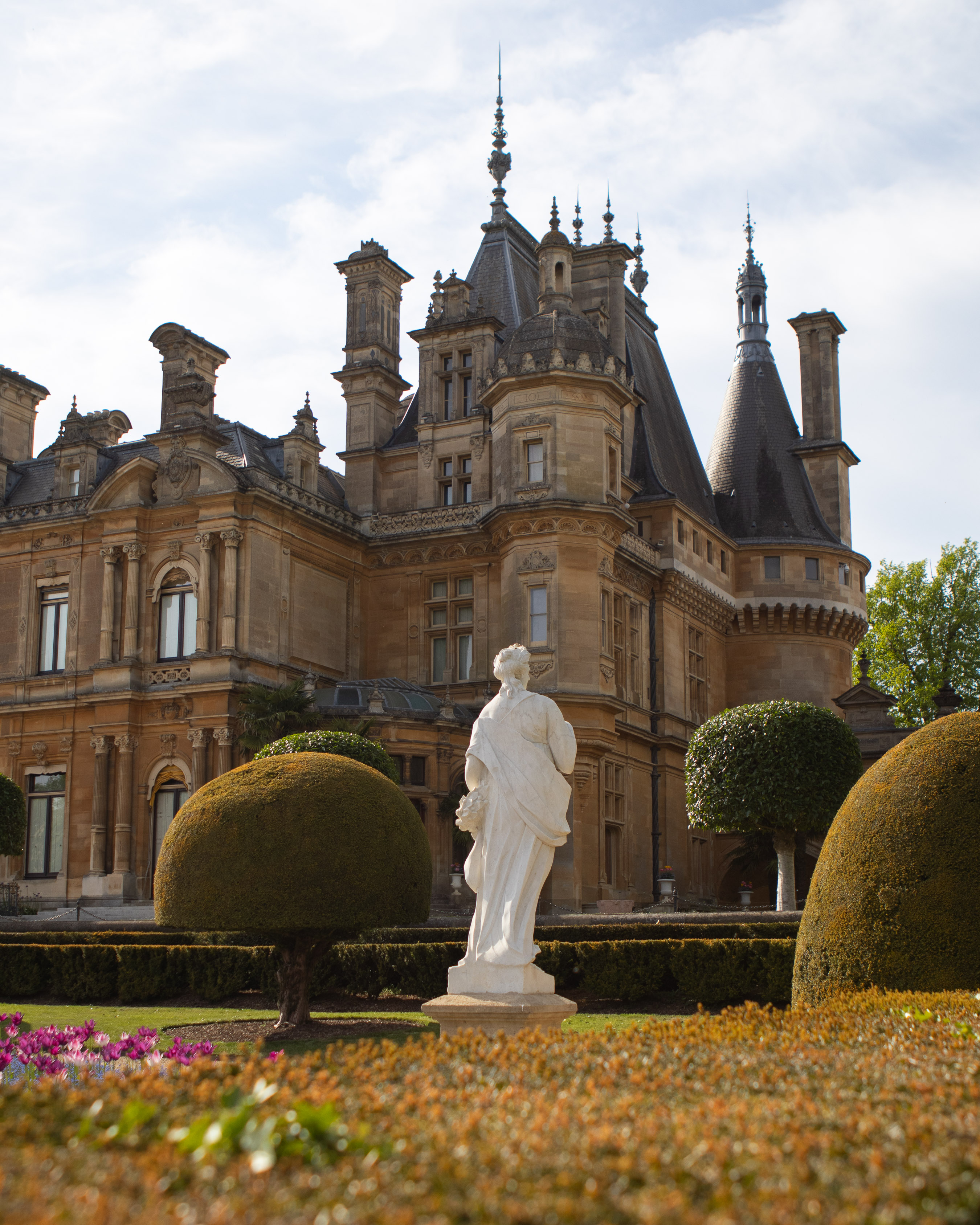 French Renaissance-style chateau with topiary gardens and classical statue at Waddesdon Manor