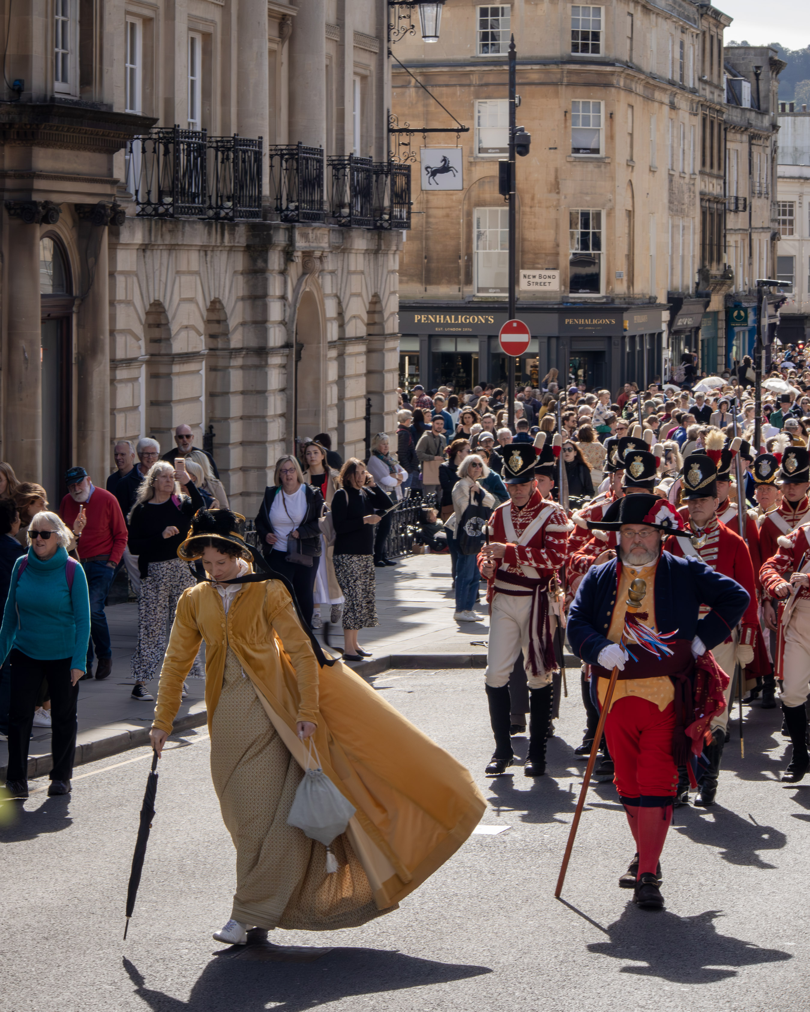 Regency-costume procession down a Georgian street in Bath on a sunny day