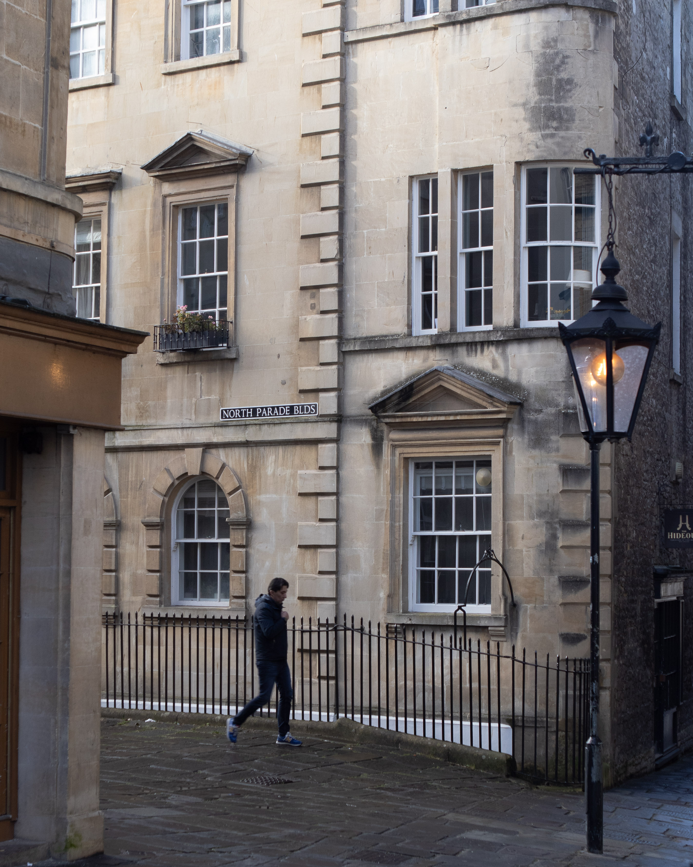 Bath street corner of Georgian Bath stone with iron lamp and 'North Parade Bldgs' sign, single figure walking past