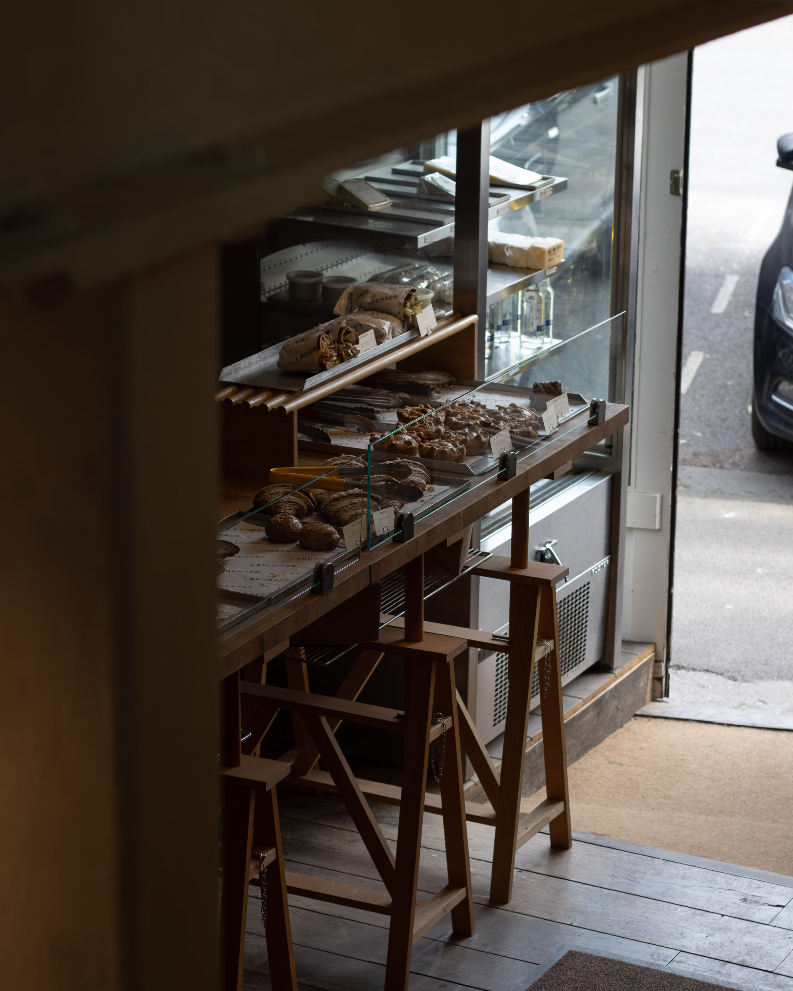 View from inside an artisan bakery looking out onto the street, sourdough loaves and pastries lined up on the counter